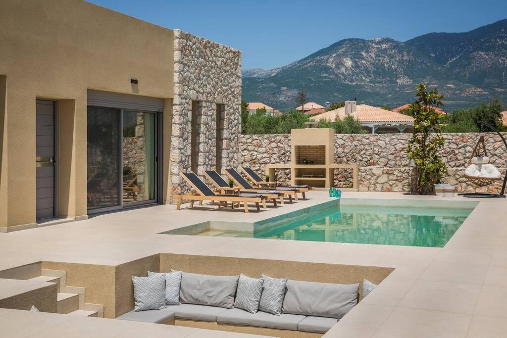 a villa with a swimming pool with mountains in the background at Villa Amarylis - Ionian Treasure Villas in Kefallonia