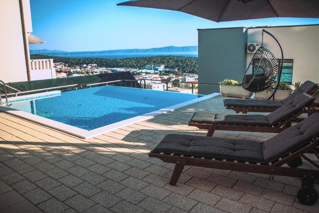 a swimming pool with two lounge chairs and an umbrella at Apartman Patricia in Makarska