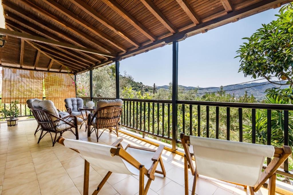 a deck with chairs and tables and a balcony with a view at Ourania Apartment in Skopelos Town