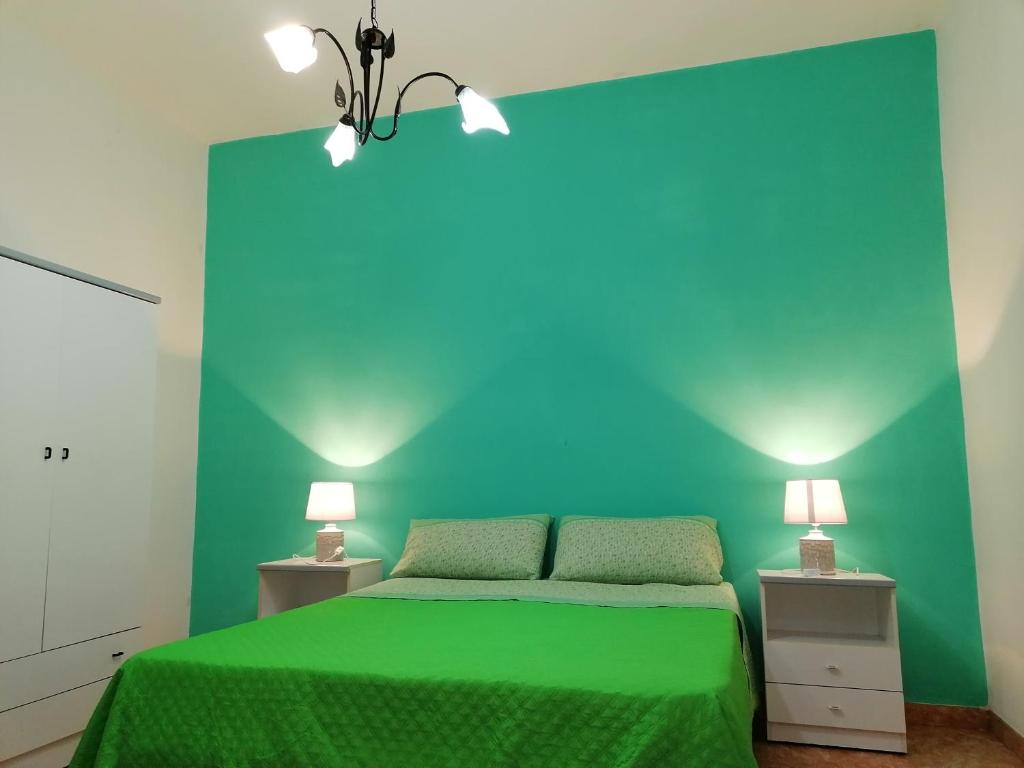 a bedroom with a green bed with two lamps at CASA MICHELE in Marinella di Selinunte