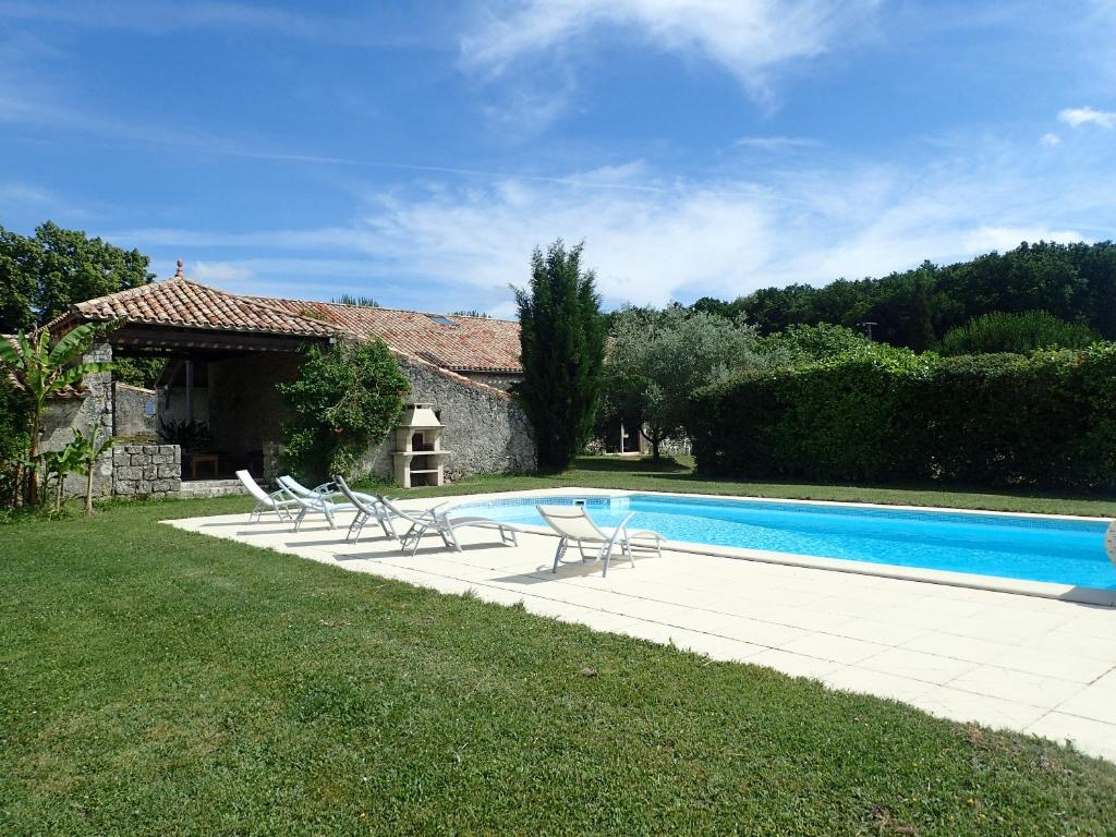 a swimming pool with chairs in front of a house at Roc du Lapin in Sainte-Colombe-de-Villeneuve