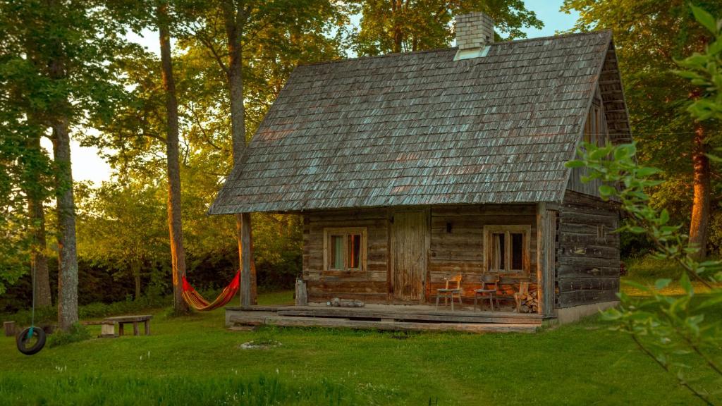 a log cabin with a hammock in the yard at Grande Tiidu Sauna House in Rõuge