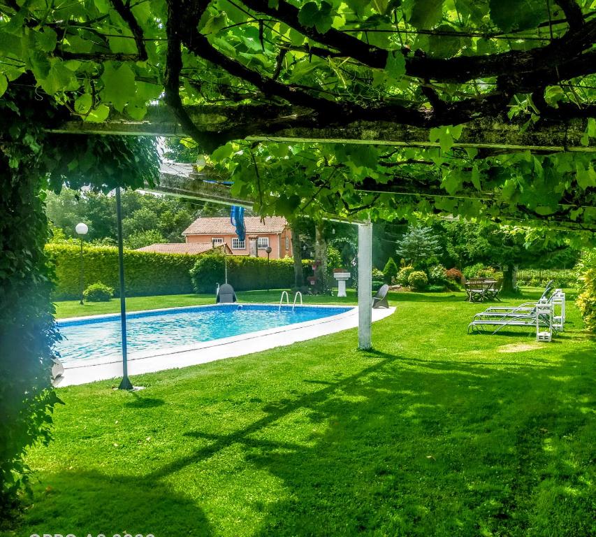 a backyard with a swimming pool and green grass at Casa Rustica Neiro in Santiago de Compostela