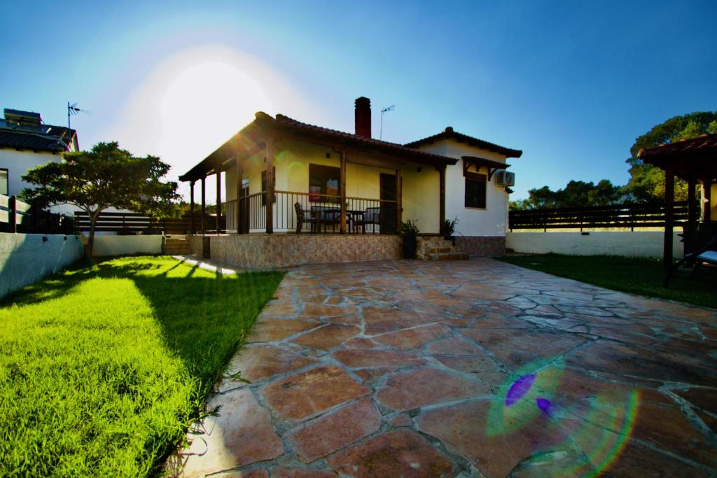 a house with a stone walkway in front of a yard at Enalio Beach House in Nea Kallikrateia