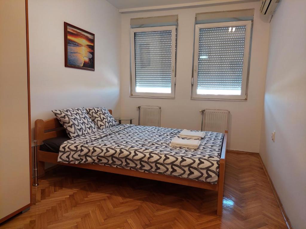 um quarto com uma cama num quarto com duas janelas em City passage apartments 2 em Novi Sad