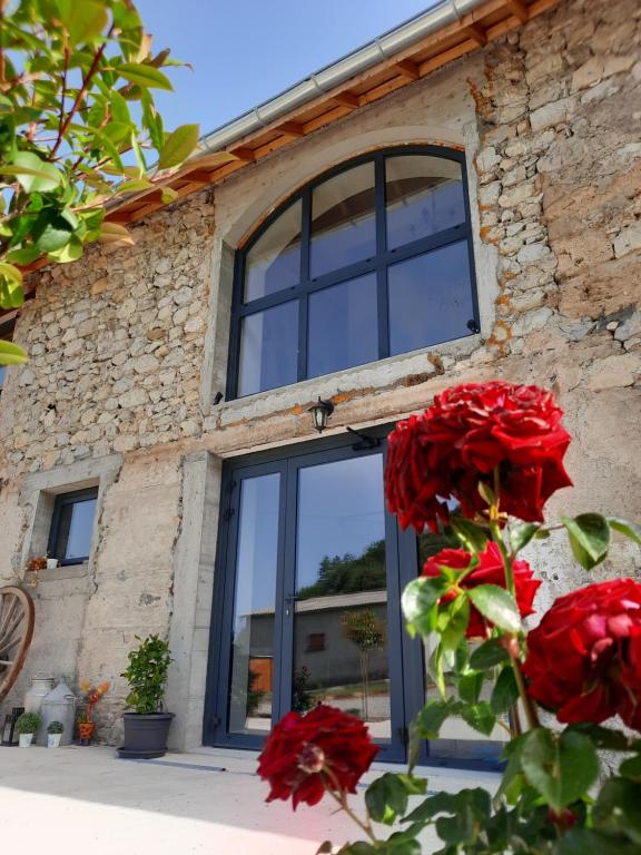 a stone building with a window and red roses at Le Petit Bégou in Saint-Auban-dʼOze