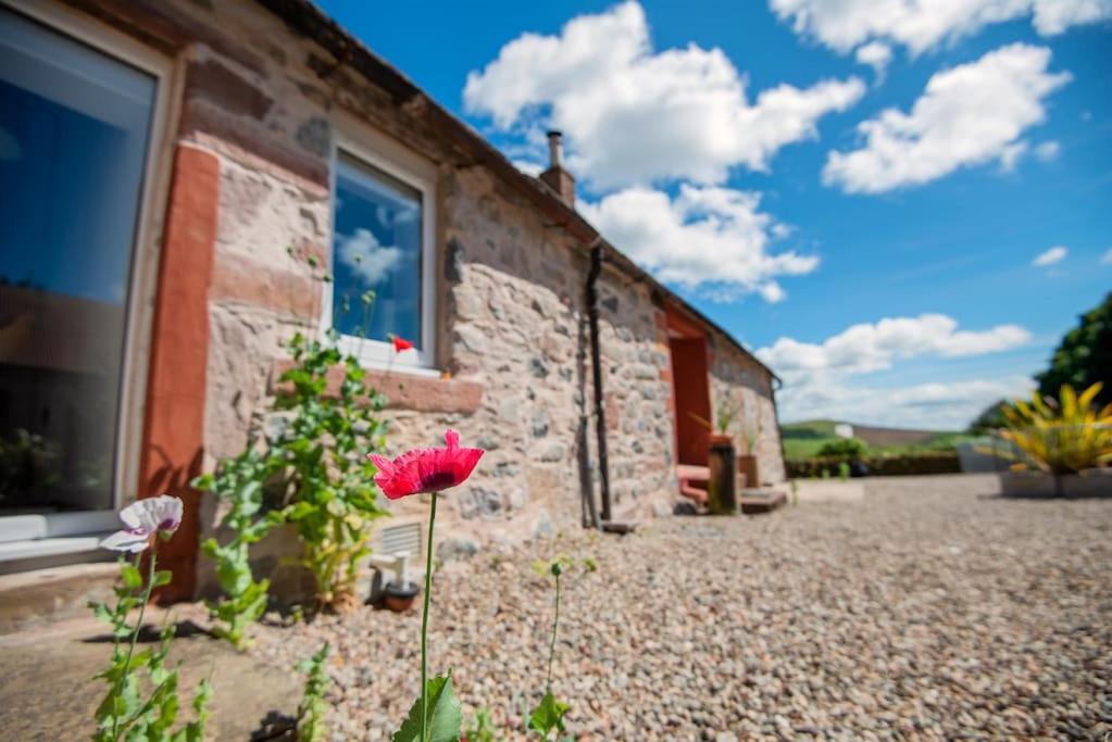 un bâtiment en pierre avec des fleurs devant lui dans l'établissement Spacious & Stylish StoneHous Cottage, à Forfar