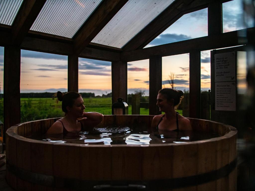 Due donne in una vasca idromassaggio con il tramonto sullo sfondo di Cosy Cottage with Spa, Catering, Nature Reserve Walks, Large Garden, Free Parking - Self Checkin a Scunthorpe