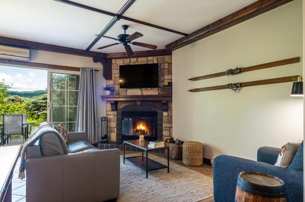 a living room with a fireplace and a tv at Le Boisé (Les Manoirs) Mont-Tremblant in Mont-Tremblant