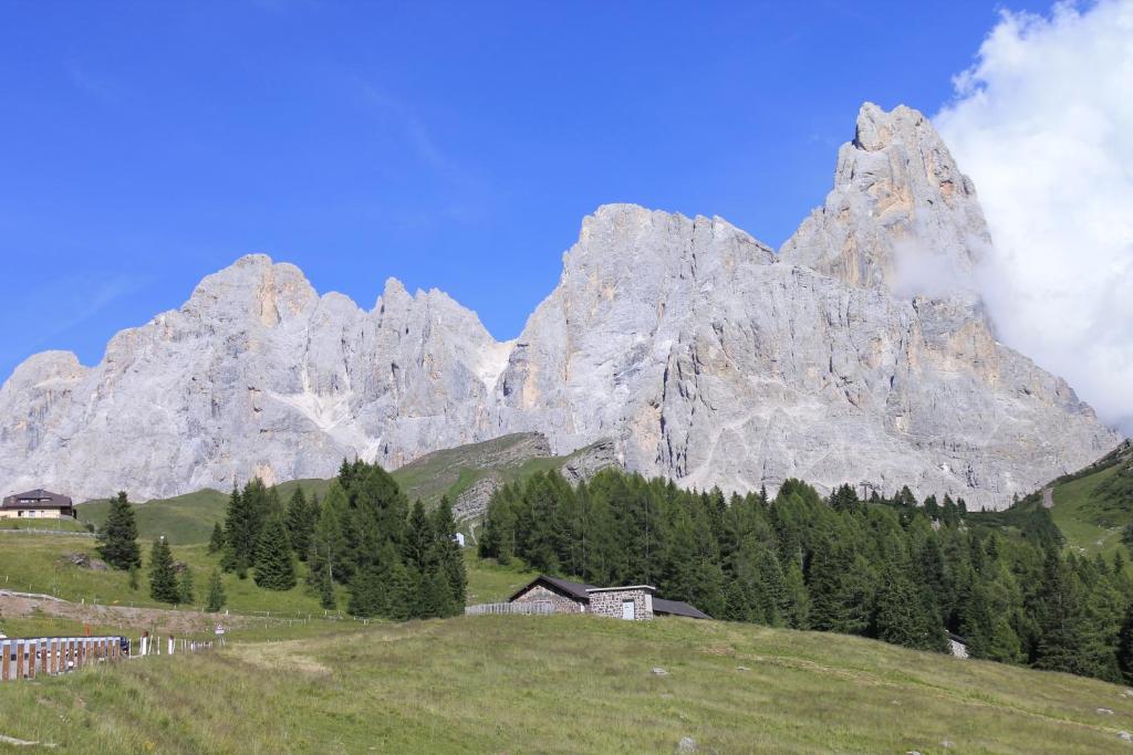 a mountain range with a house on a green field at LA PULCE INNEVATA - Mansarda a due passi dal cielo - Dolomiti Affitti in Passo Rolle