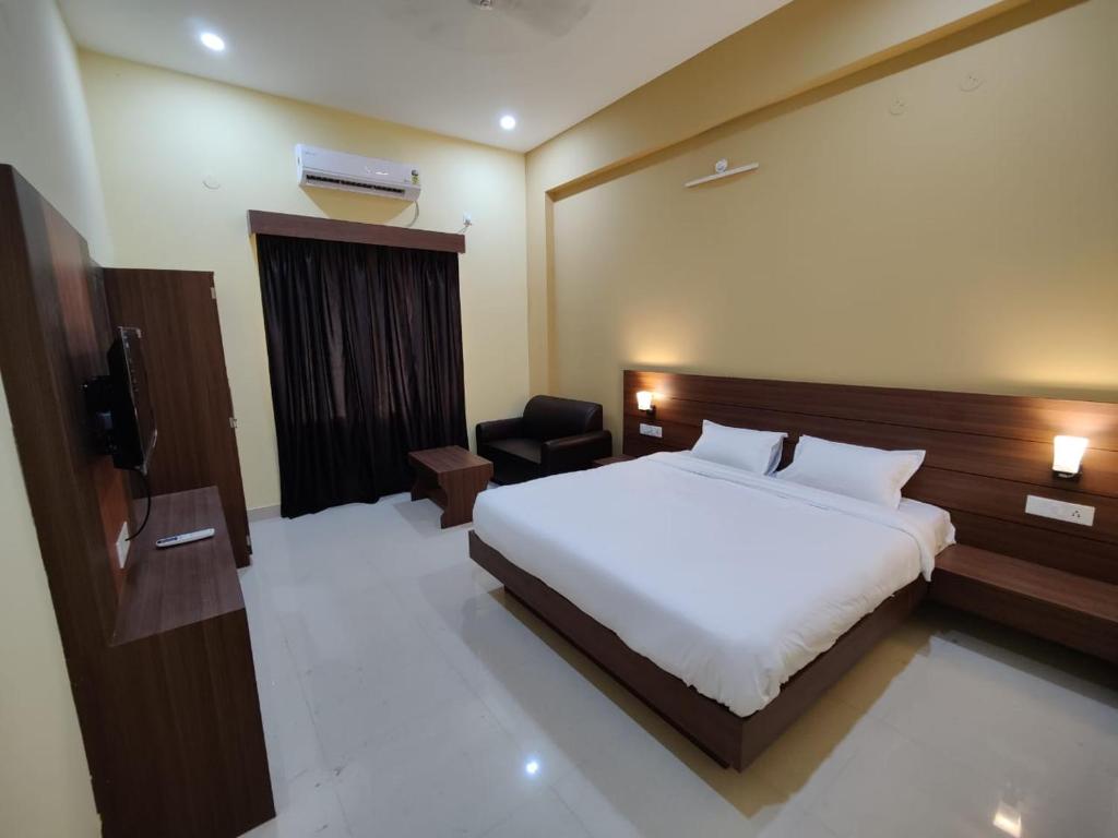 ein Hotelzimmer mit einem Bett und einem Stuhl in der Unterkunft HR Garden(Hotel & Resort) in Deoghar