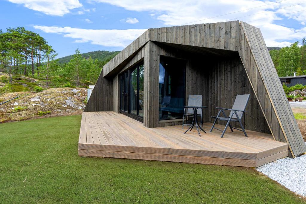 mały drewniany dom z 2 krzesłami na tarasie w obiekcie Sogndal Fjordpanorama - Studio Cabins With View w mieście Sogndal