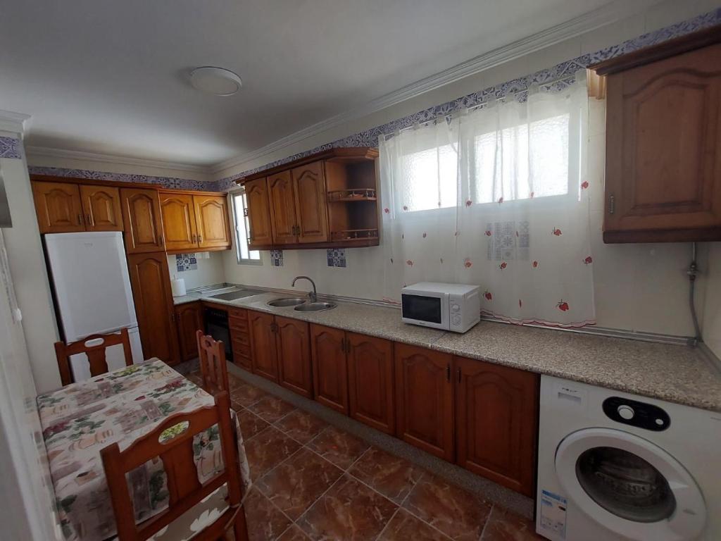 eine Küche mit Holzschränken, einer Spüle und einer Waschmaschine in der Unterkunft piso villavarela in Tarifa