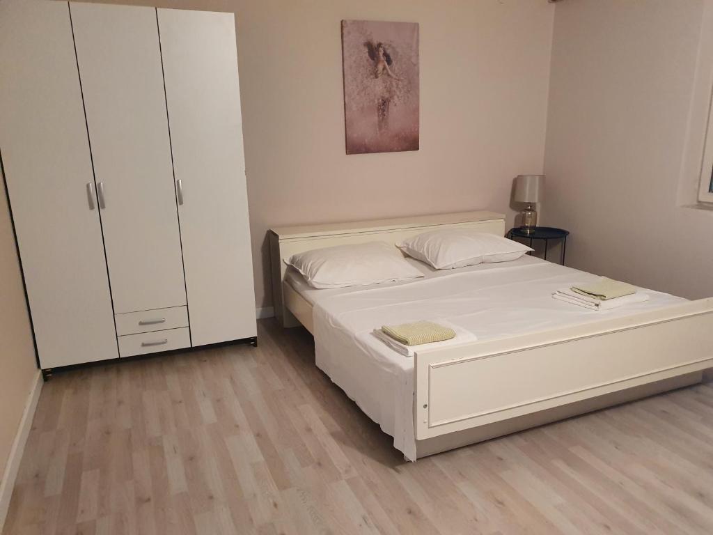 a bedroom with a white bed and a cabinet at apartman Luka in Sinj