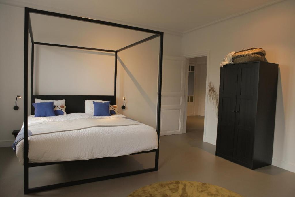 a bedroom with a canopy bed with blue pillows at MAISON KITOKO in Ghent