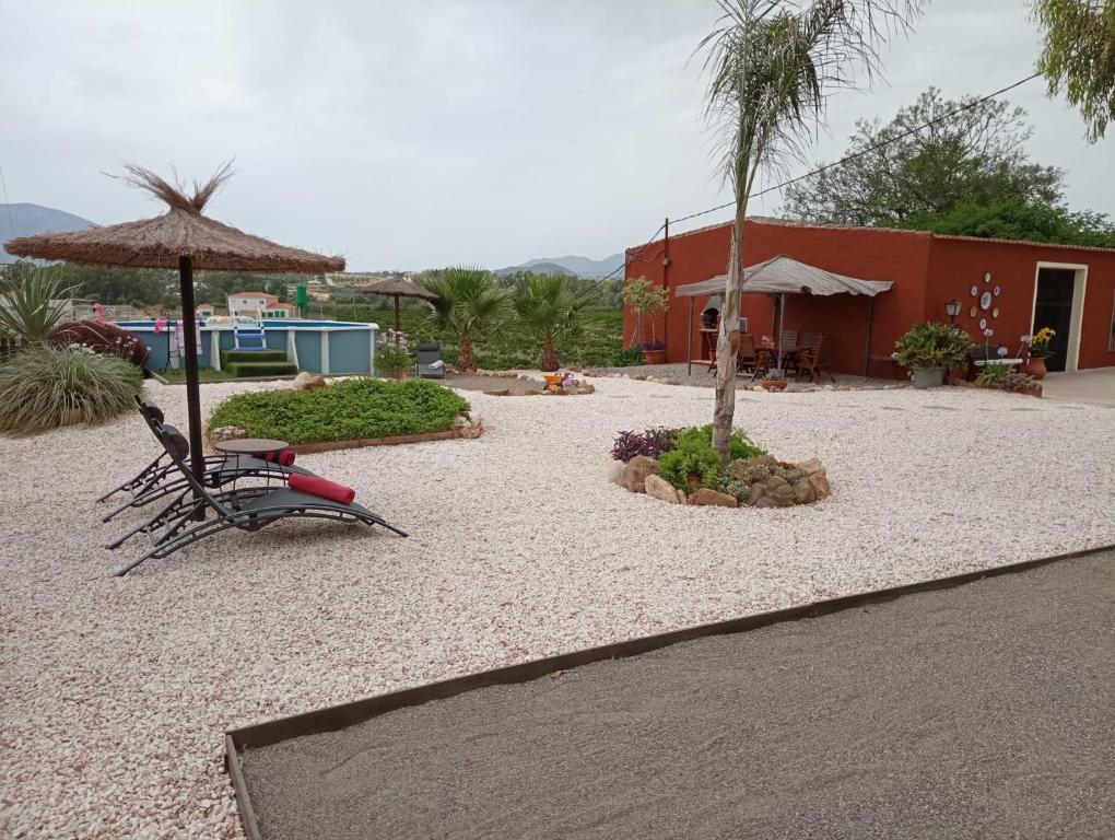 ein Resort mit Stühlen, einem Sonnenschirm und einem Gebäude in der Unterkunft Home Benitez Pizarra in Pizarra