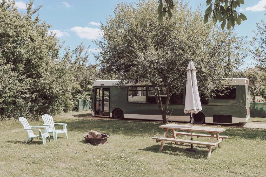 Levaré的住宿－Relaxing retreat for 2 on beautiful converted bus，一张野餐桌和一辆巴士旁边的雨伞