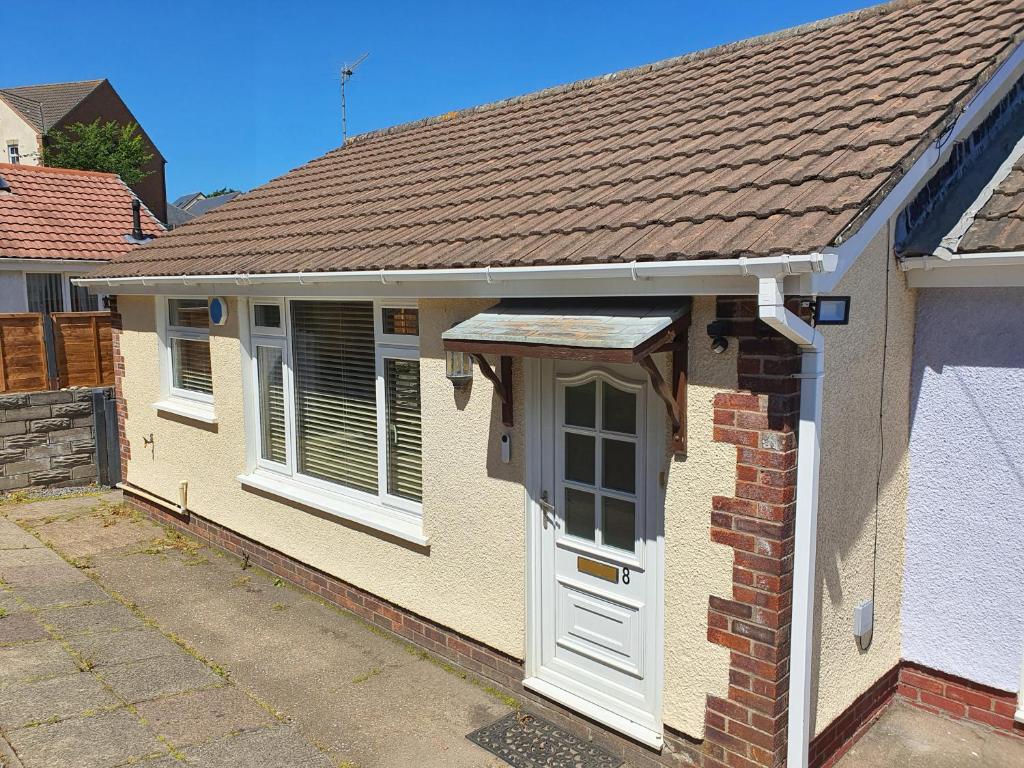 a brick house with a white door and windows at Captivating 2 bedroom bungalow in mumbles in Swansea