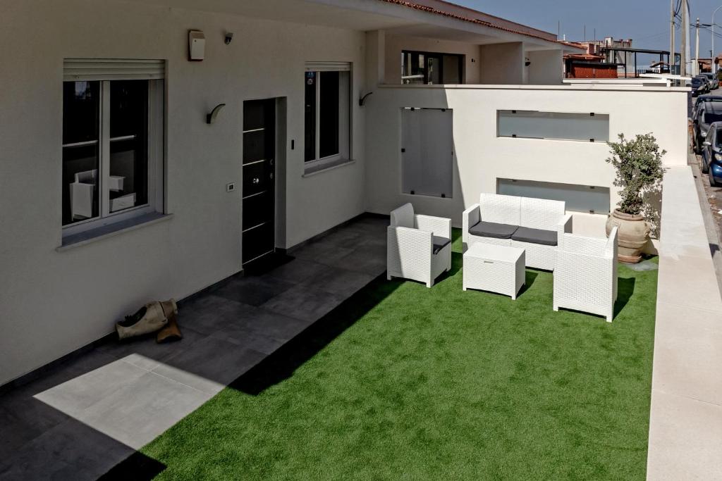 a patio with white chairs and green grass at AL BAYDA in Palermo