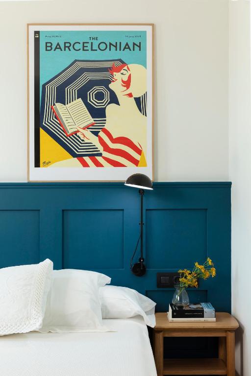 a bed with a blue head board with a poster at Som Nit Port Vell in Barcelona