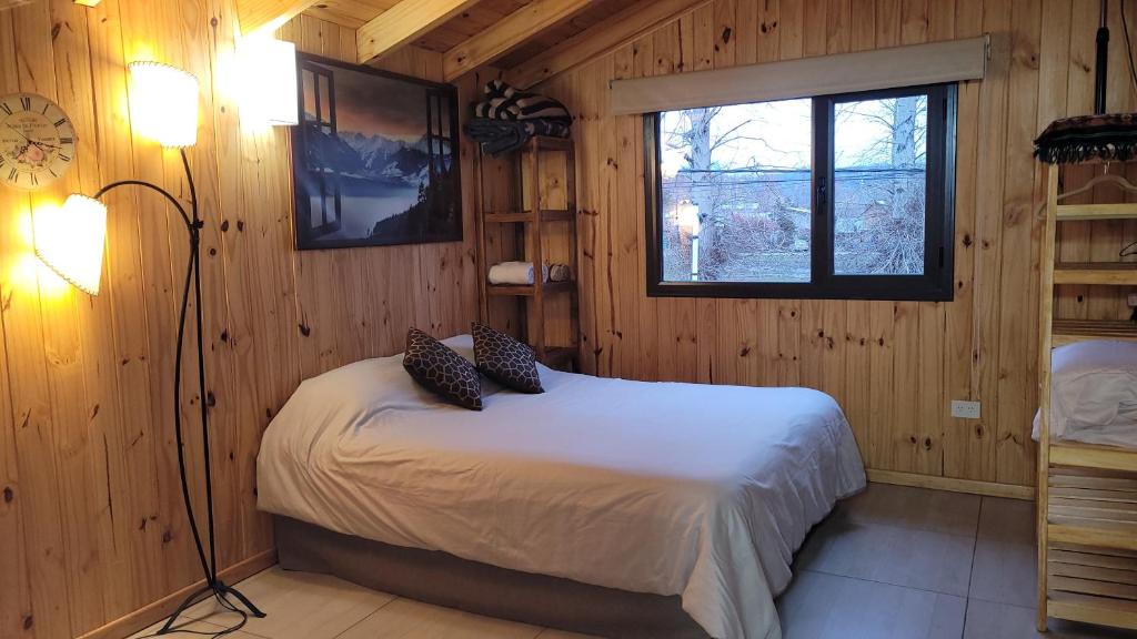 um quarto com uma cama num chalé de madeira em Espacio BERNI em San Martín de los Andes