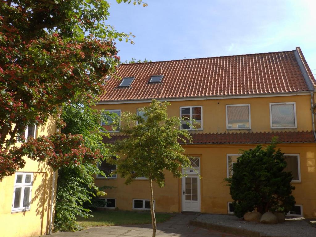 ein gelbes Haus mit rotem Dach in der Unterkunft Vestergade 7 Holiday Apartments in Frederikshavn