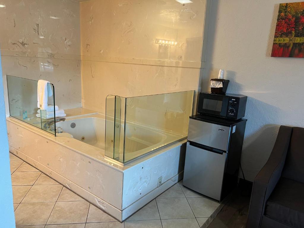 a bath tub in a room with a microwave at Red Carpet Inn Medford in Medford
