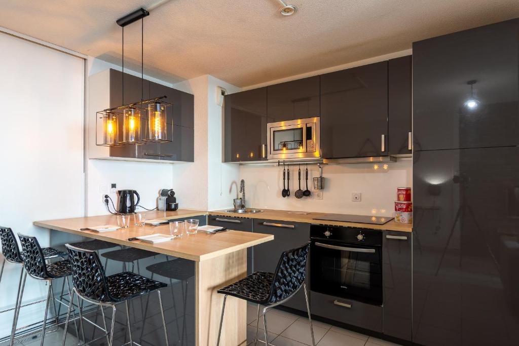 a kitchen with black cabinets and a island with bar stools at Appart cosy(4pers)PARKING CLIM Terrasse Vélodrome in Marseille