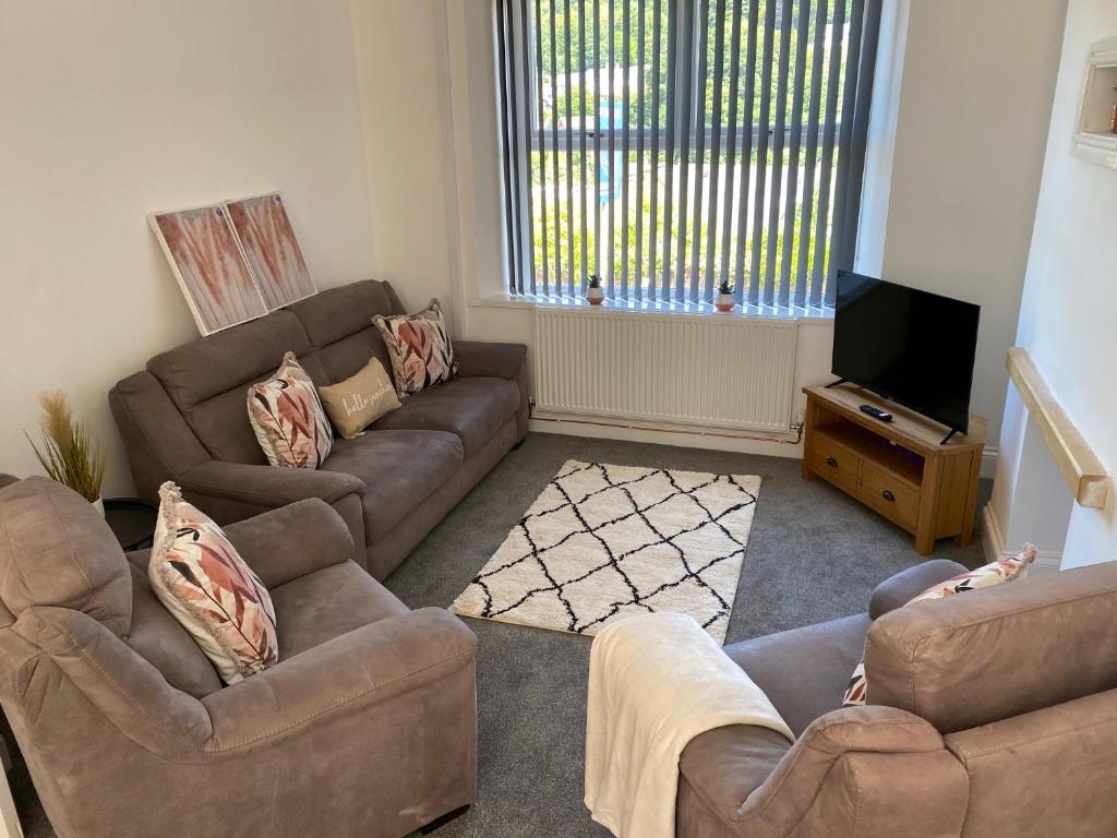 a living room with two couches and a flat screen tv at Mitchell Heights in Pontnewynydd