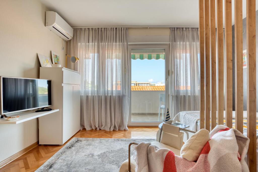 uma sala de estar com televisão e uma grande janela em Cozy studio in Petrovac with sea view em Petrovac na Moru