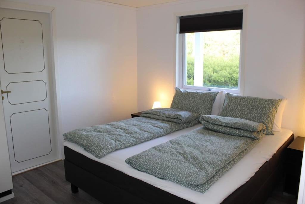 a bed with pillows on it in a room with a window at Romslig og fin leilighet 17 min til Kristiansand Centrum in Nodeland