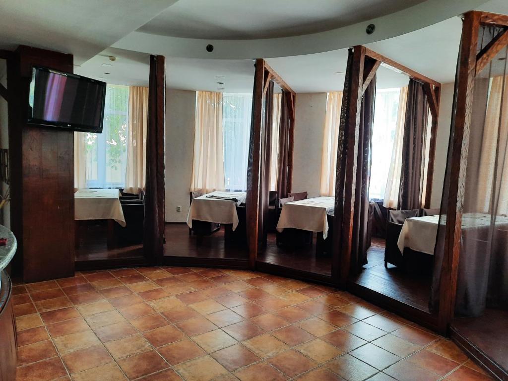 a room with two tables and a tv and mirrors at Готельно-ресторанний комплекс «Тополя» in Zwiahl