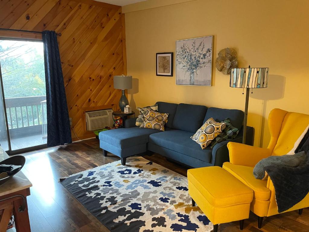 uma sala de estar com um sofá azul e uma cadeira amarela em Village at Winnipesaukee 59 Treetop #432 em Laconia