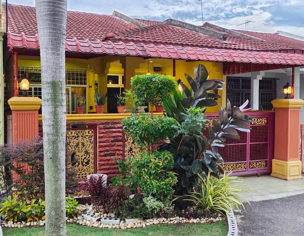 uma casa amarela e vermelha com plantas à sua frente em Faridah Homestay Melaka Muslim Friendly em Kampong Bukit Katil