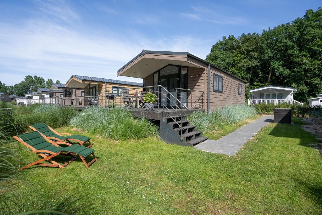 une cabane en bois avec une terrasse et un banc dans l'herbe dans l'établissement Ostseecamp Lübecker Bucht Casa del Mar mit kostenfreier Saunanutzung, à Scharbeutz
