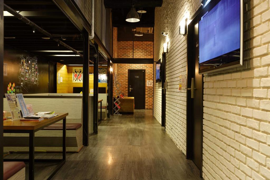 a hallway with a table and a tv on a brick wall at Angels Hostel Taipei Ximen in Taipei