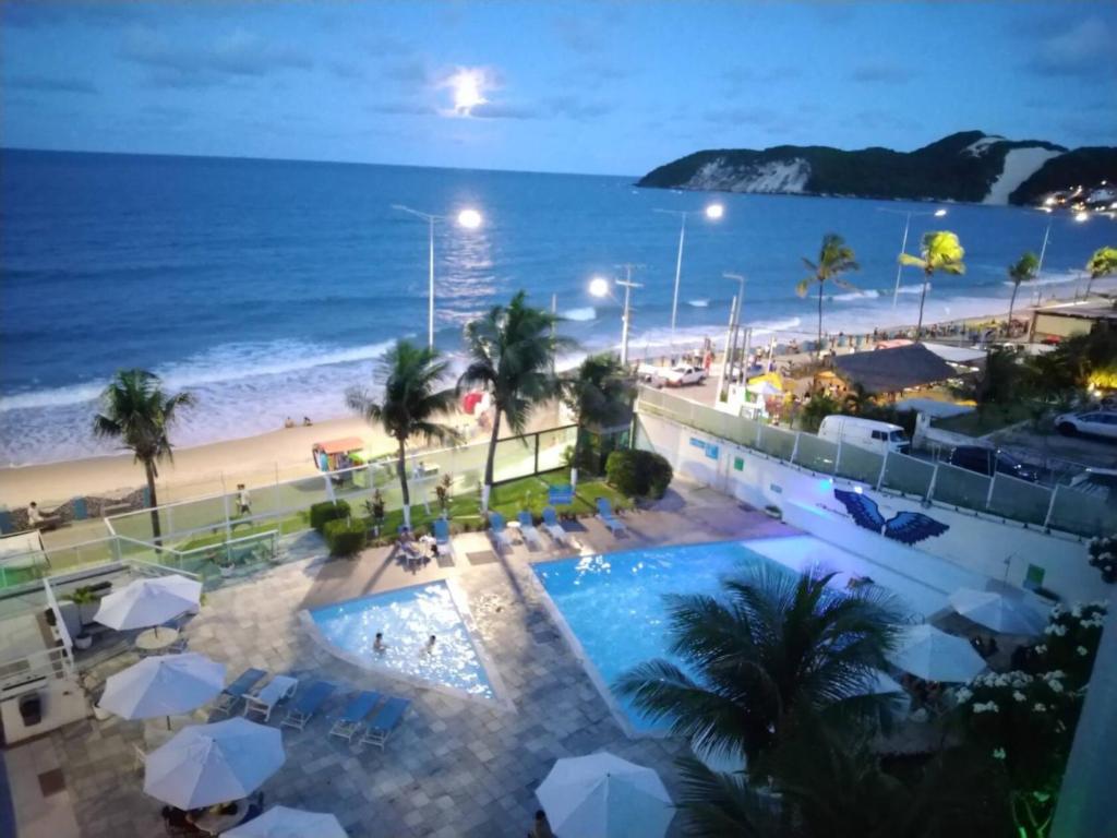 uitzicht op een zwembad en het strand in de nacht bij FLAT PONTA NEGRA BEACH-Natal in Natal