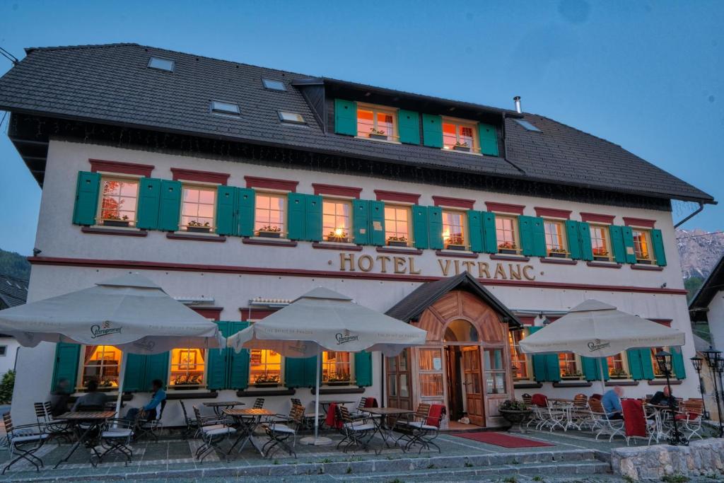 a hotel with tables and umbrellas in front of it at Vitranc Boutique Hotel in Kranjska Gora