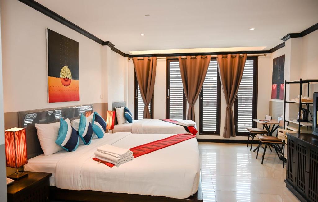 a bedroom with two beds in a room with windows at Queen Boutique Hotel Chaweng in Chaweng