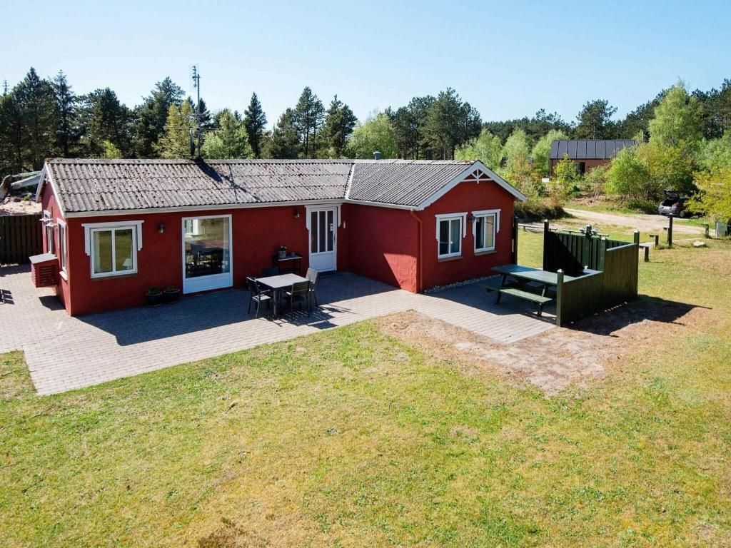 uma casa vermelha com um pátio e um quintal em 5 person holiday home in R m em Rømø Kirkeby