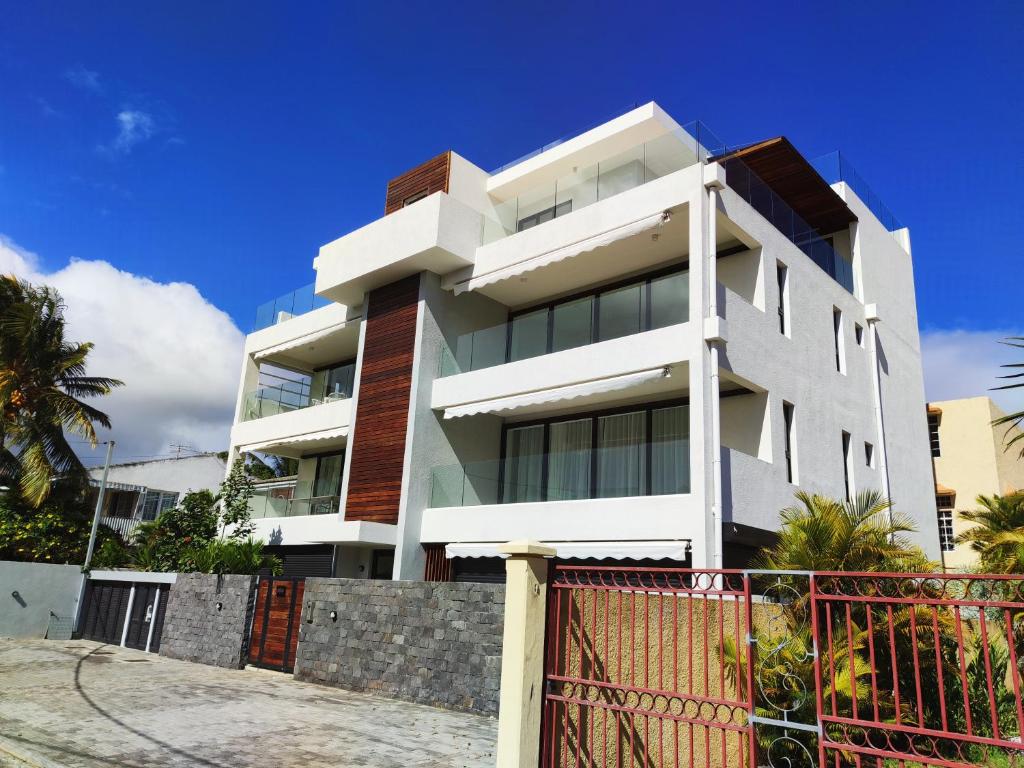 um edifício branco com uma cerca em frente em Appartement neuf à Trou aux Biches em Trou-aux-Biches