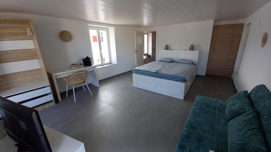 a bedroom with a bed and a desk and a couch at Aloha chambres in Port-Valais
