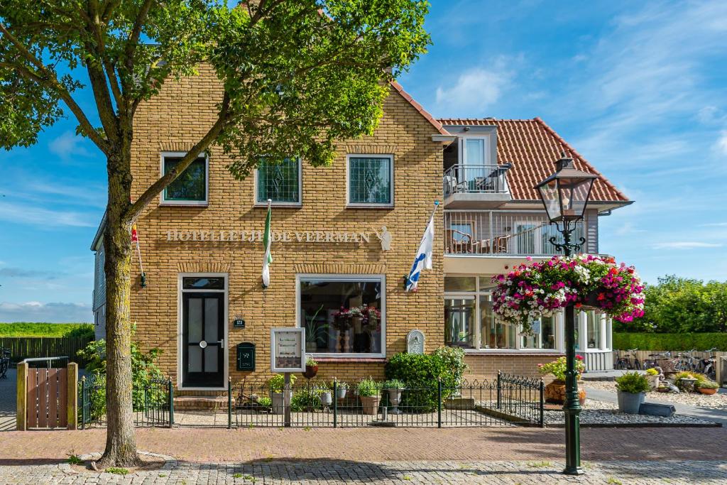 una casa de ladrillo con un árbol delante de ella en Hotelletje de Veerman en Oost-Vlieland