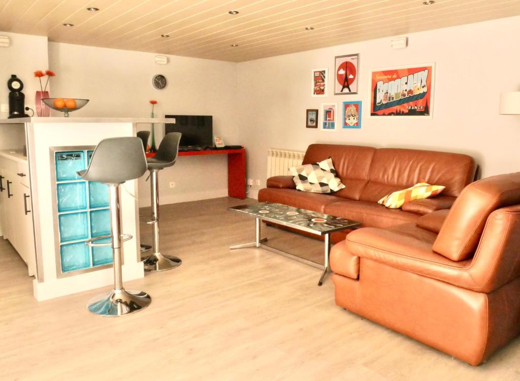 sala de estar con sofá de cuero marrón y mesa en Bordeaux centre historique: Charmant Duplex, en Burdeos