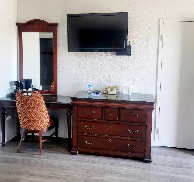 a dresser with a television and a desk with a chair at Economy inn in Corning