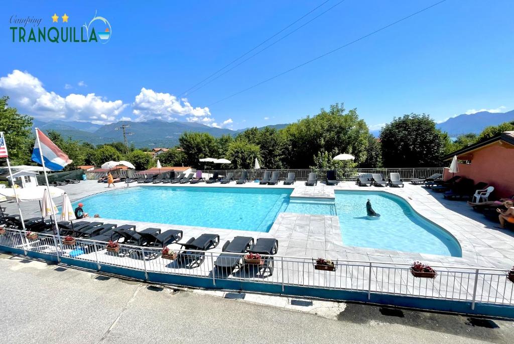 une grande piscine entourée de chaises longues. dans l'établissement Campeggio Tranquilla, à Baveno