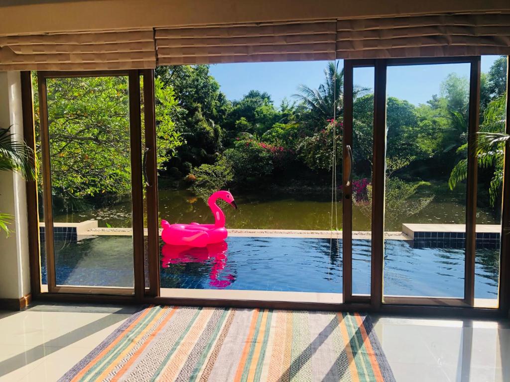 un flamenco rosa en el agua fuera de una ventana en Pool Villas by Honey-5 miles from central Pattaya Beach, en Nong Prue