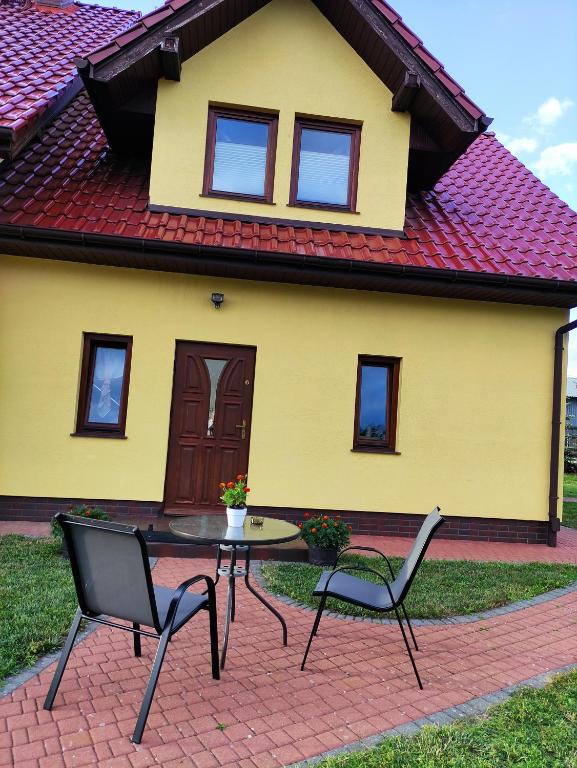 una mesa y sillas frente a una casa amarilla en Apartament Pod Lasem, en Police