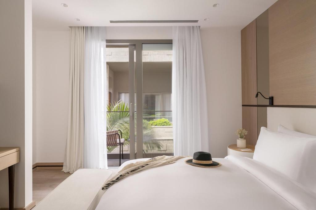 a bedroom with a large white bed and a window at METT Hotel & Beach Resort Bodrum in Bodrum City