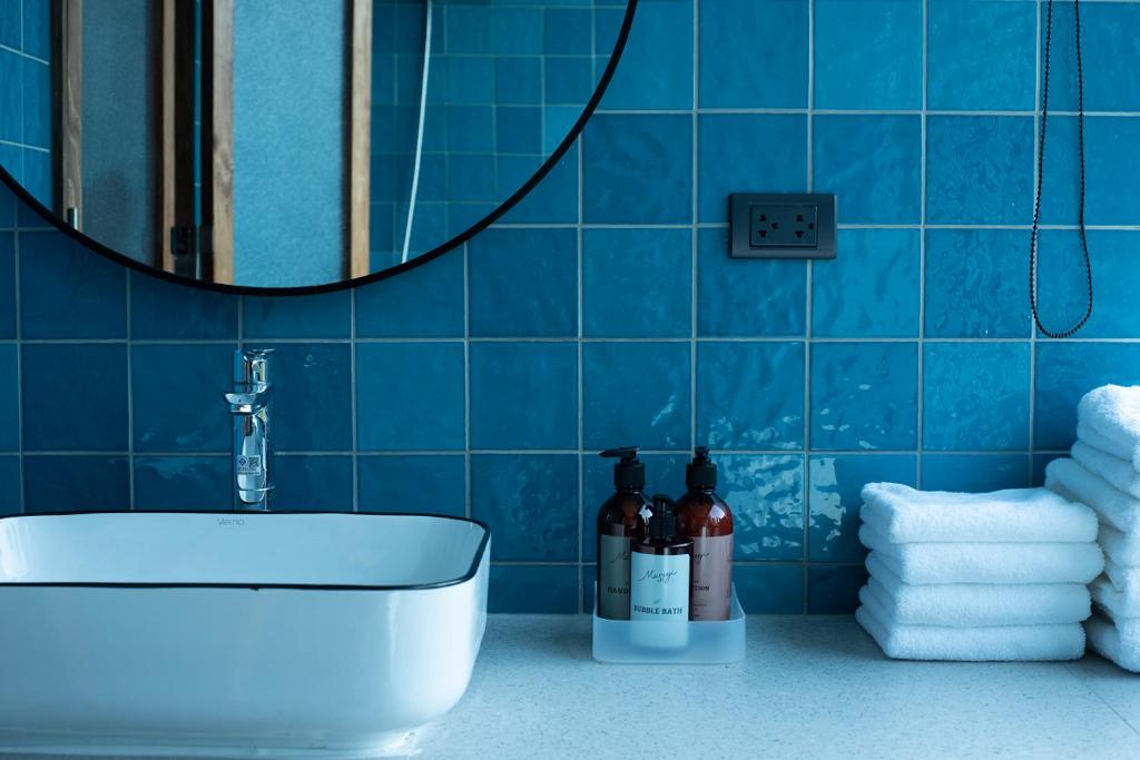 y baño con lavabo, espejo y azulejos azules. en karaarom hotel, en Bangkok